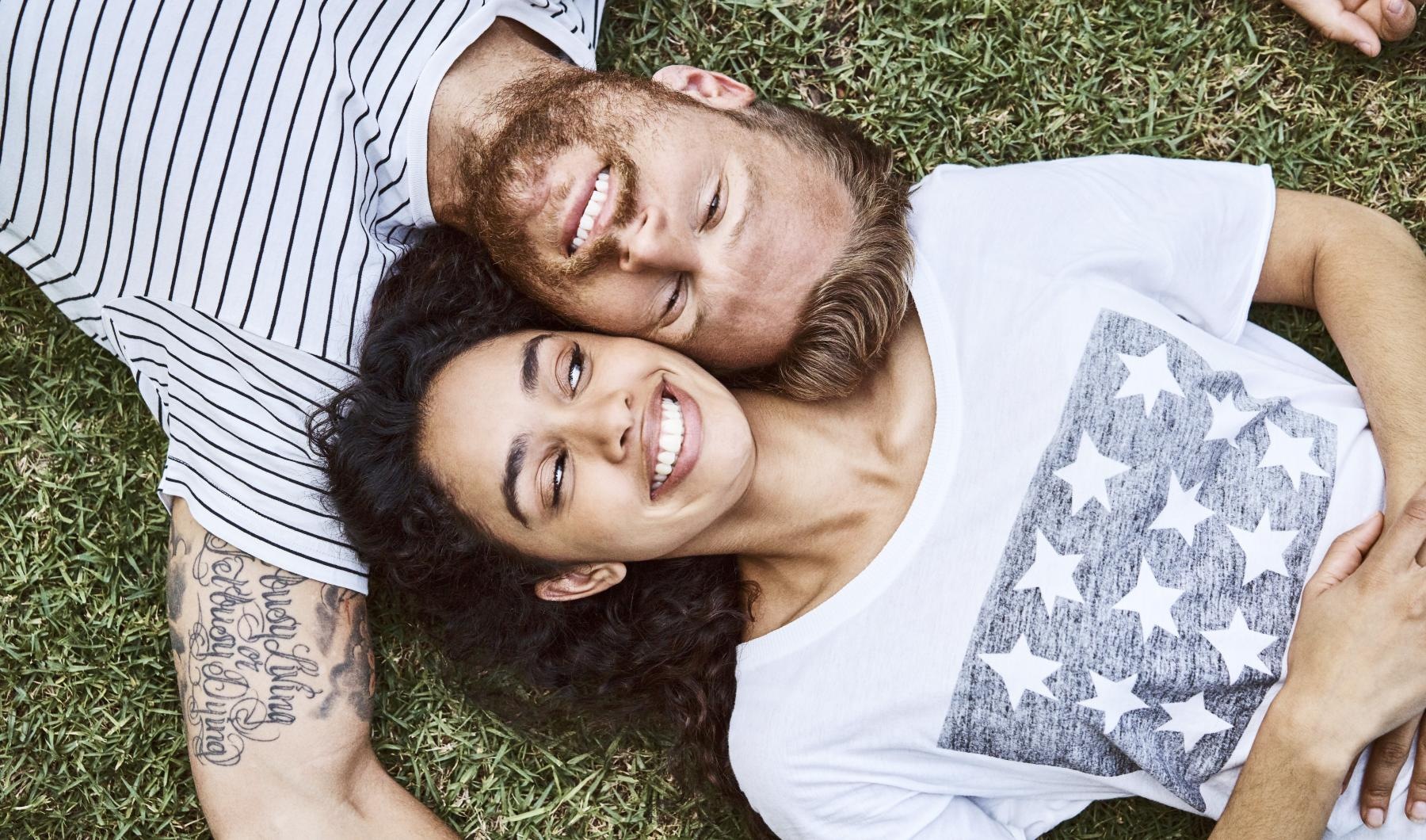 a man and woman lying in the grass