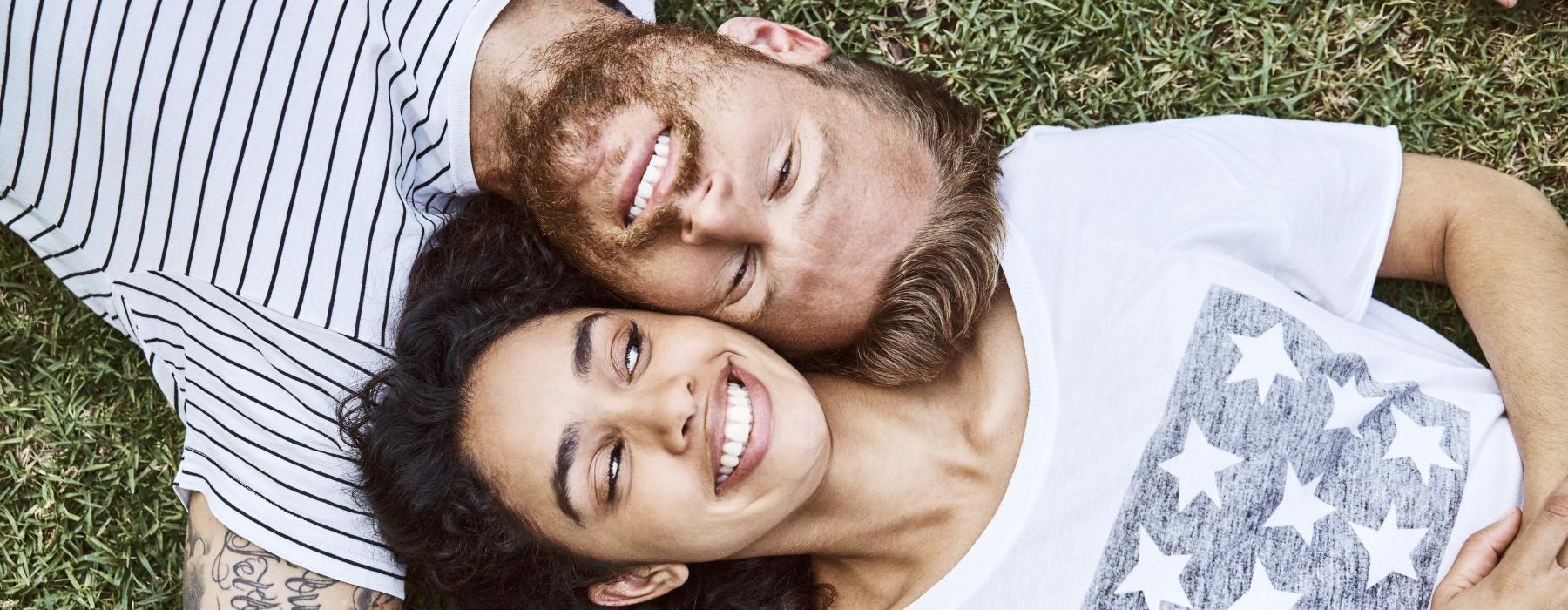 a man and woman lying in the grass