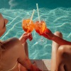 two friends spending time by the pool with drinks